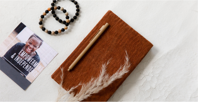 Layout of barkcloth notebook, pen, bead bracelets, and impact card. 