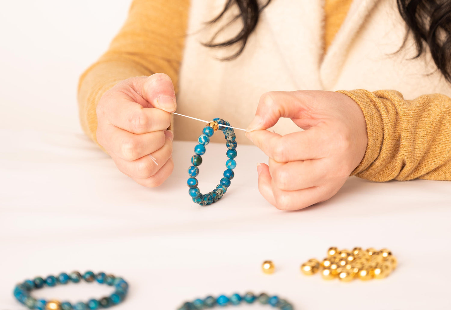Women's hands creating bracelets for employee gifting. 