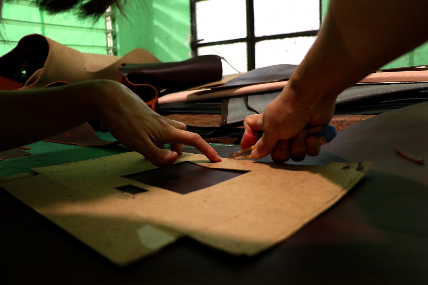 Hand-crafter's measuring and cutting leather for bags, laptop cases, and other goods. 