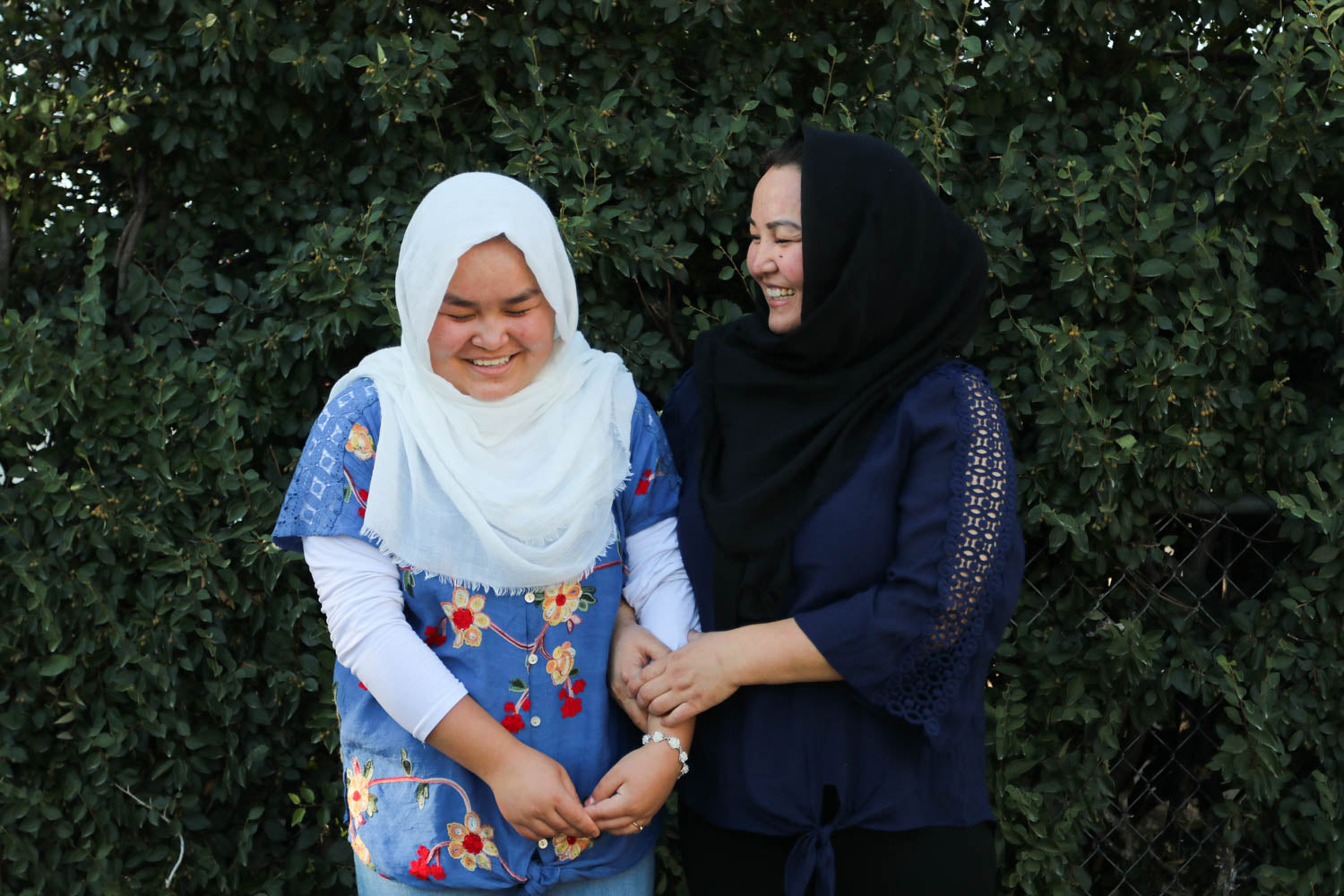 Two women in Hijab holding hands and laughing. 