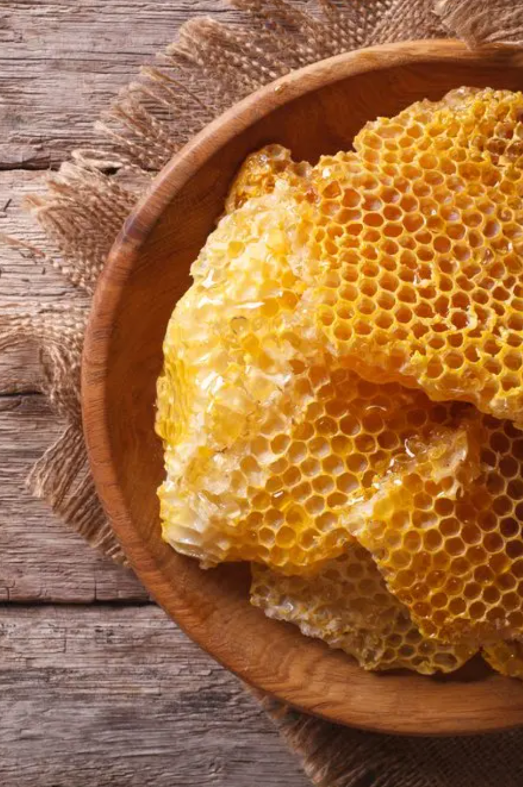 Fresh honeycomb in a wooden bowl on a table. 