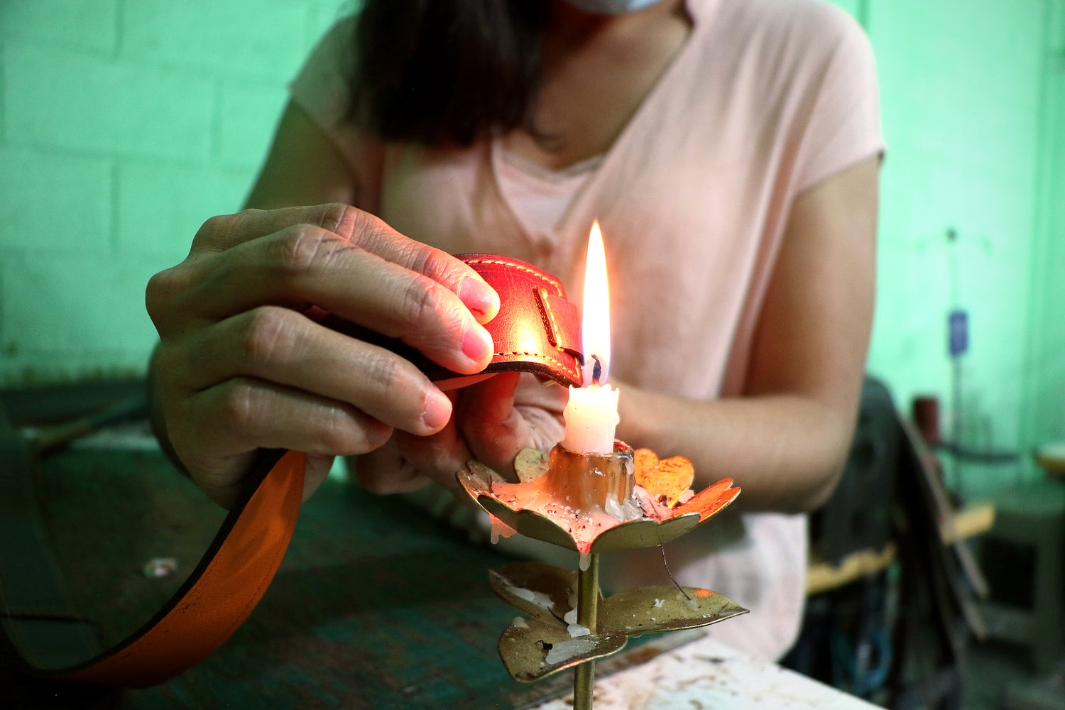 A woman holding a piece of a leather bag to a flame for branding purposes. 